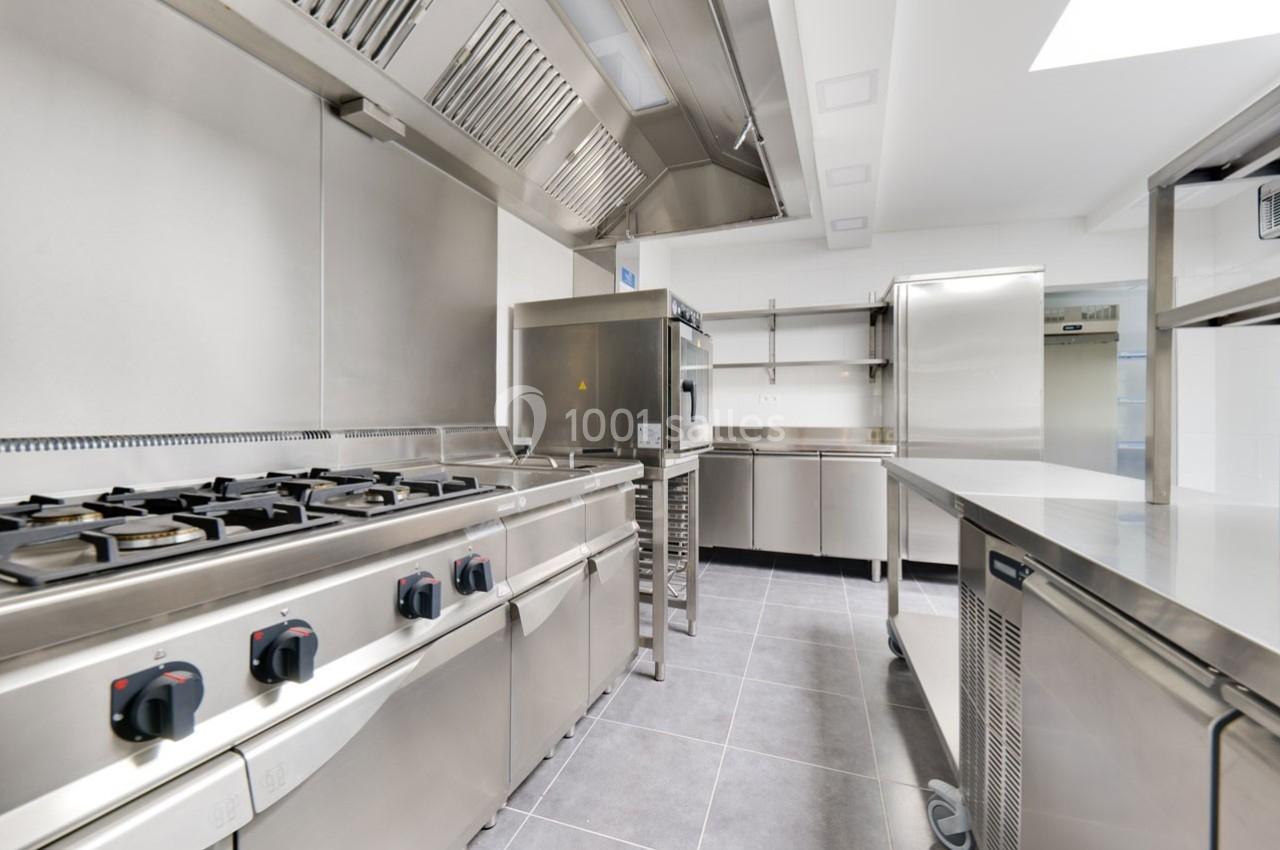 Cuisine professionnelle moderne avec équipements en acier inoxydable, comprenant plaques de cuisson, fours et plans de…