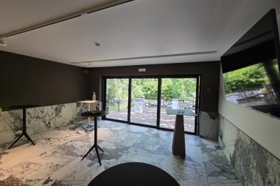 Des personnes discutent debout dans un espace extérieur, entourées de verdure et de mobilier de jardin.