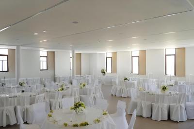 Salle de réception lumineuse avec des tables rondes dressées de nappes blanches et décorées de fleurs.