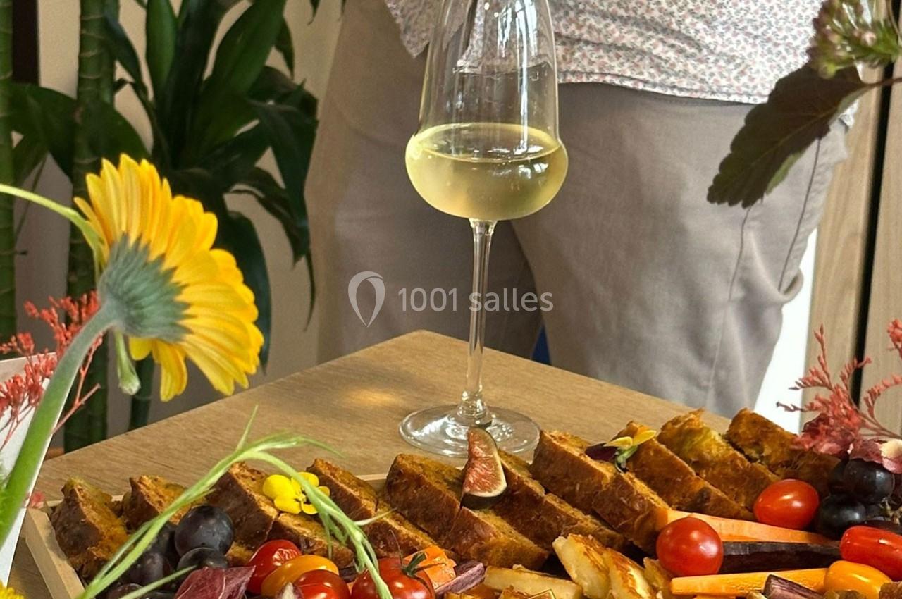 Plateau de légumes, fruits et tartes salées sur une table en bois, avec un verre de vin blanc à côté.