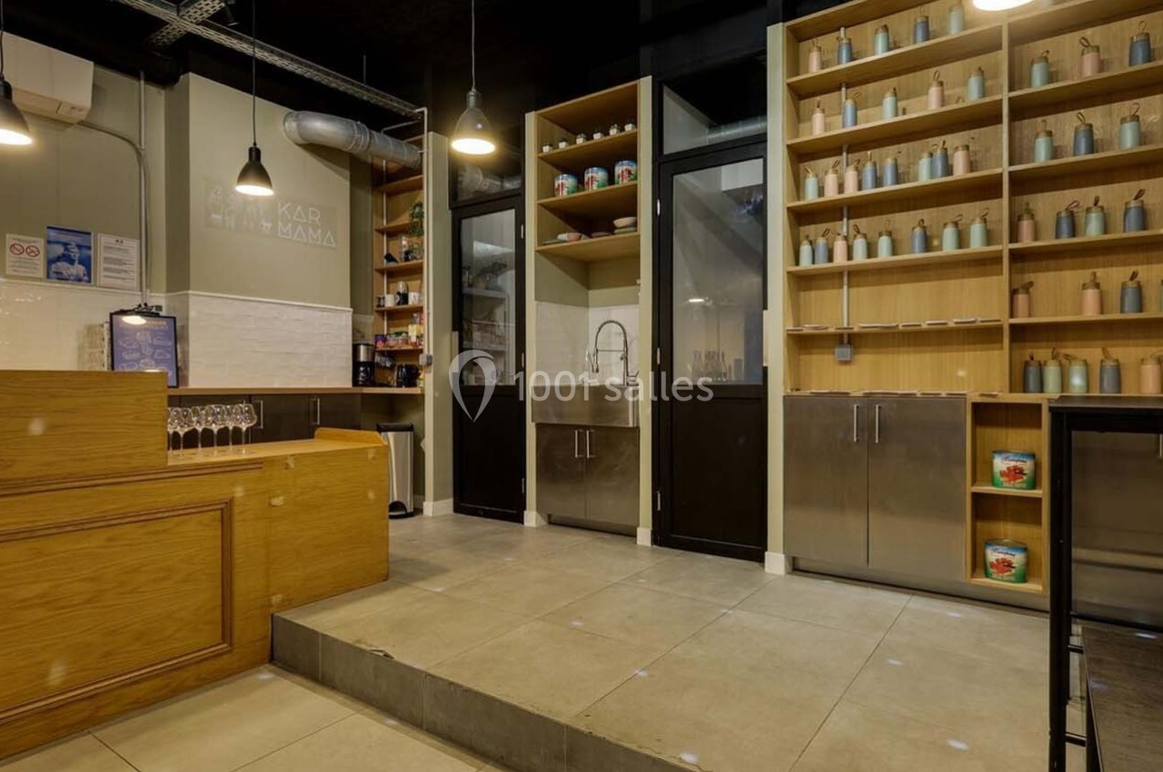 Intérieur d'un magasin avec comptoir en bois, étagères remplies de bouteilles et évier en arrière-plan.