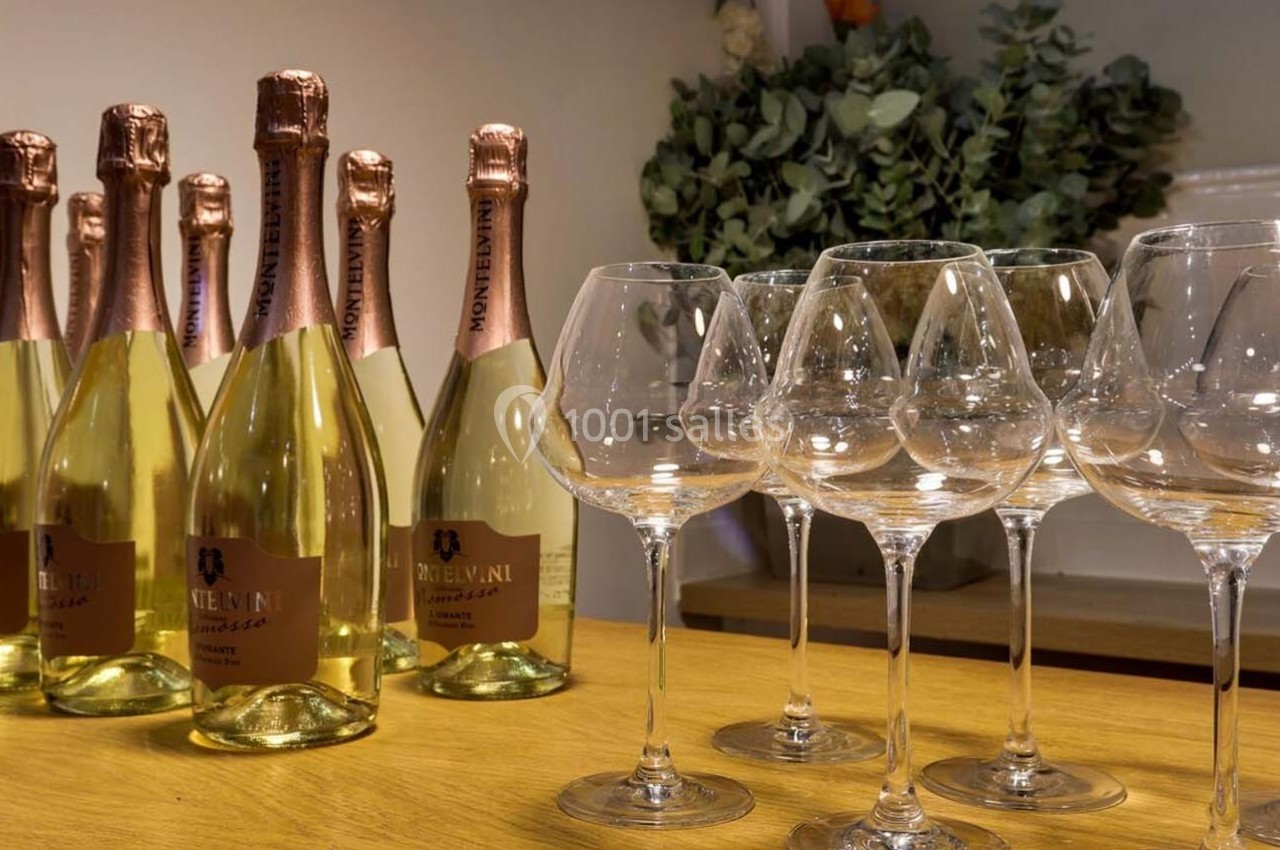 Bouteilles de vin mousseux alignées sur un comptoir en bois avec des verres à pied vides à côté.