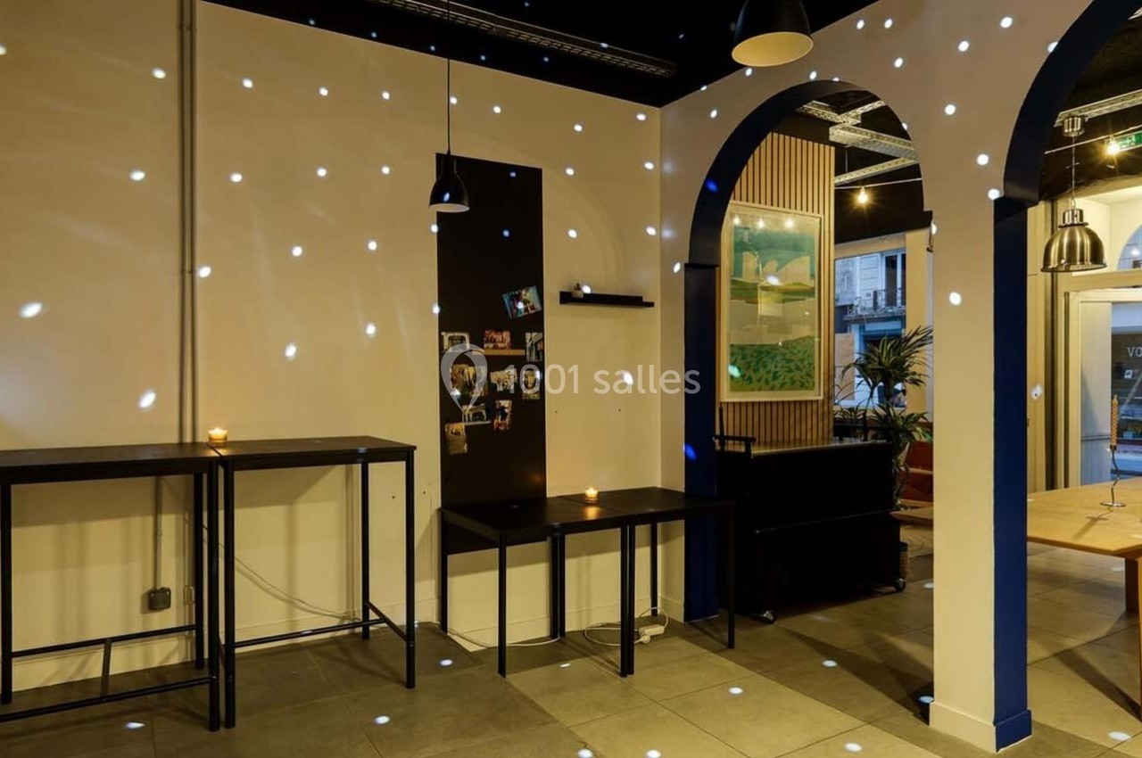 Intérieur d'une pièce avec des tables, des étagères et des points lumineux projetés sur les murs et le sol.