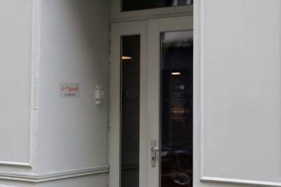 Façade d'un restaurant avec une vitrine éclairée, une porte centrale et des affiches de plats sur la droite.