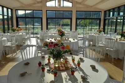 Terrasse extérieure avec tables dressées sous des parasols, entourée de végétation et de fleurs au premier plan.