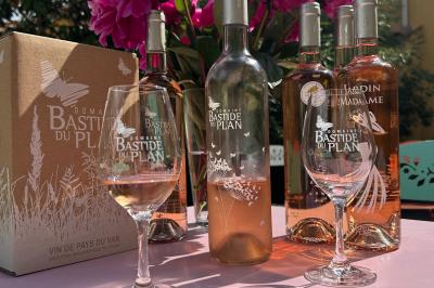 Terrasse extérieure avec tables dressées sous des parasols, entourée de végétation et de fleurs au premier plan.