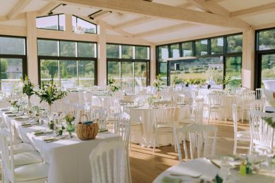 Terrasse extérieure avec tables dressées sous des parasols, entourée de végétation et de fleurs au premier plan.