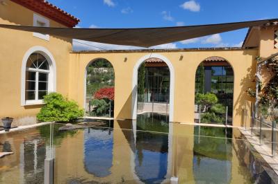 Terrasse extérieure avec tables dressées sous des parasols, entourée de végétation et de fleurs au premier plan.
