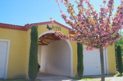 Terrasse extérieure avec tables dressées sous des parasols, entourée de végétation et de fleurs au premier plan.