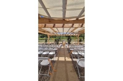 Terrasse extérieure avec tables dressées sous des parasols, entourée de végétation et de fleurs au premier plan.