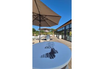 Terrasse extérieure avec tables dressées sous des parasols, entourée de végétation et de fleurs au premier plan.