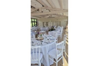 Terrasse extérieure avec tables dressées sous des parasols, entourée de végétation et de fleurs au premier plan.