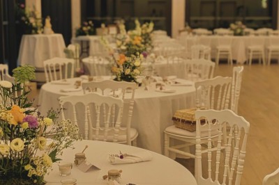 Terrasse extérieure avec tables dressées sous des parasols, entourée de végétation et de fleurs au premier plan.