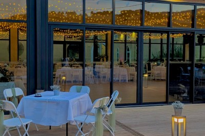 Terrasse extérieure avec tables dressées sous des parasols, entourée de végétation et de fleurs au premier plan.