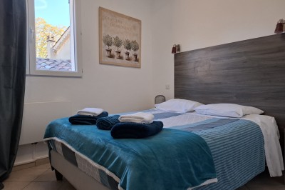 Vue d'un lac entouré de collines verdoyantes, avec quelques bateaux amarrés et un ciel partiellement nuageux.