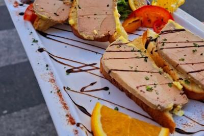 Vue d'un lac entouré de collines verdoyantes, avec quelques bateaux amarrés et un ciel partiellement nuageux.