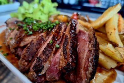 Vue d'un lac entouré de collines verdoyantes, avec quelques bateaux amarrés et un ciel partiellement nuageux.