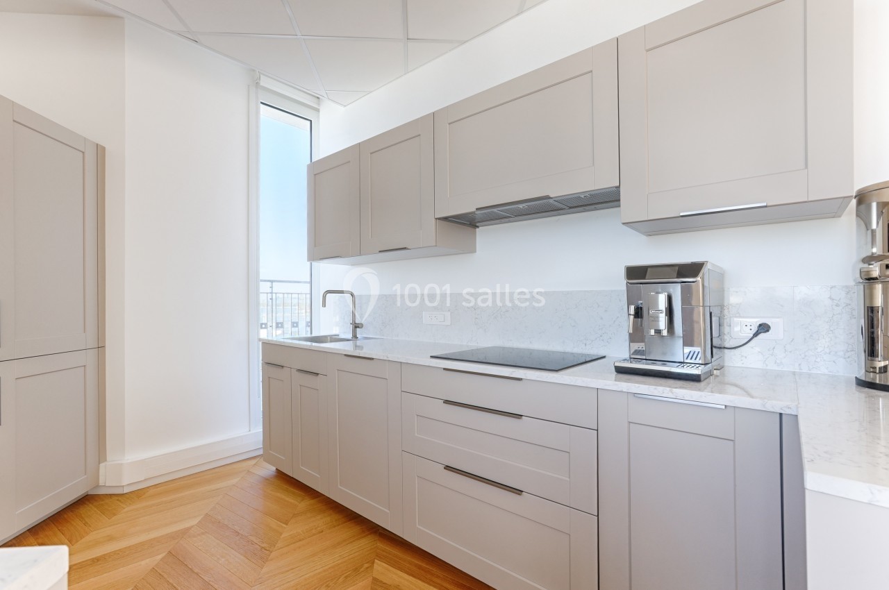 Cuisine moderne avec meubles gris, plan de travail en marbre, plaque de cuisson, évier et machine à café.