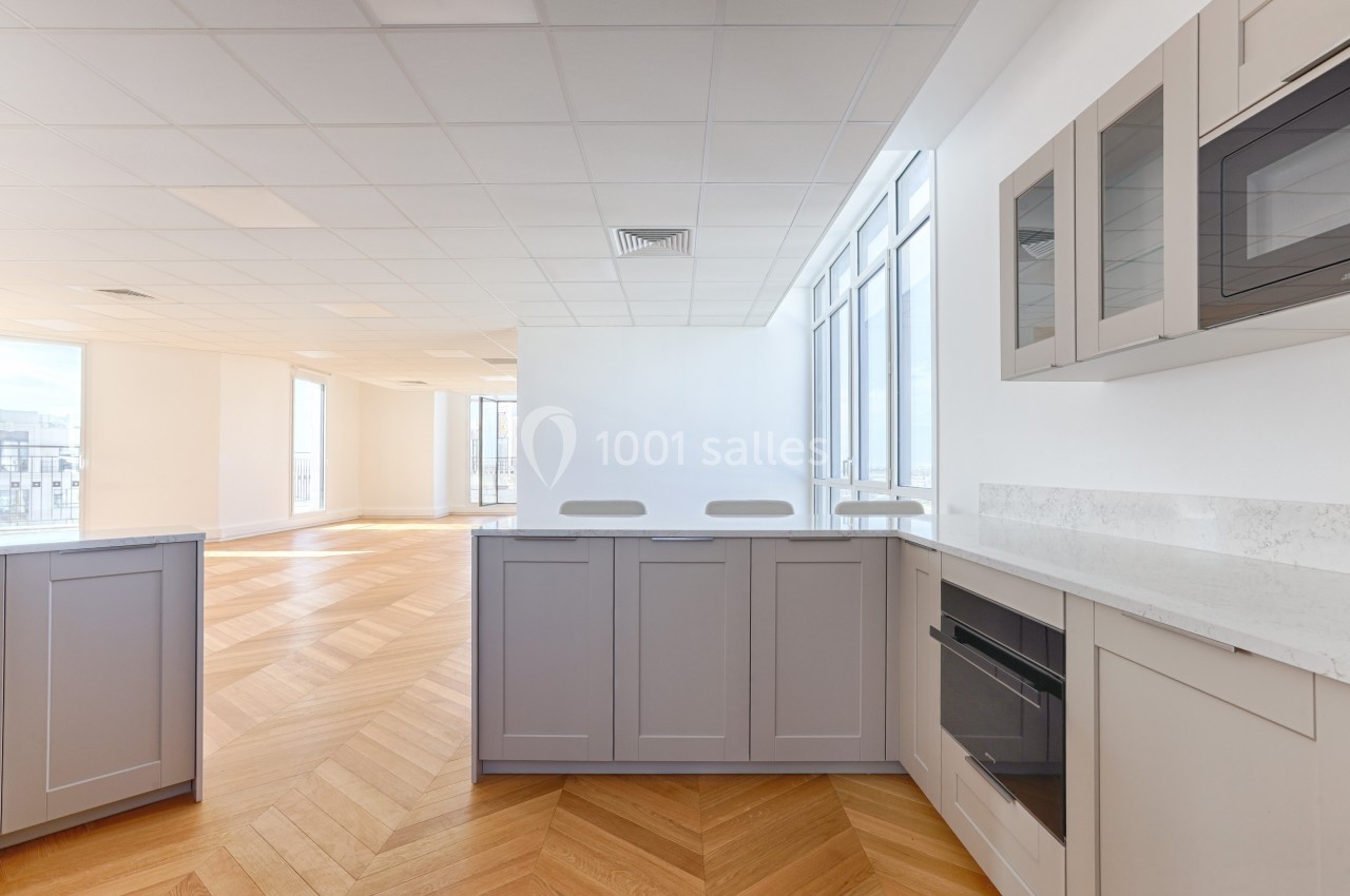 Cuisine moderne avec meubles gris, plan de travail en marbre, parquet en bois clair et grandes fenêtres lumineuses.