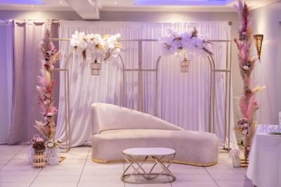 Centre de table avec structure dorée, bouquet de roses pastel et verres disposés sur une table dressée.