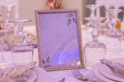 Centre de table avec structure dorée, bouquet de roses pastel et verres disposés sur une table dressée.