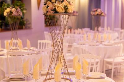 Centre de table avec structure dorée, bouquet de roses pastel et verres disposés sur une table dressée.