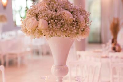 Centre de table avec structure dorée, bouquet de roses pastel et verres disposés sur une table dressée.