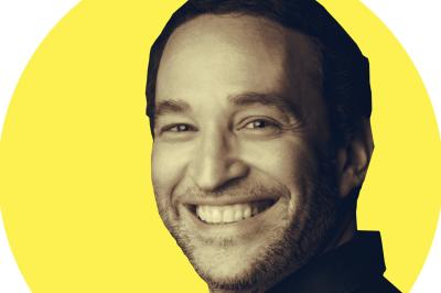 Table de jeu de casino avec tapis vert numéroté et porte-gobelets intégrés, entourée de personnes debout.