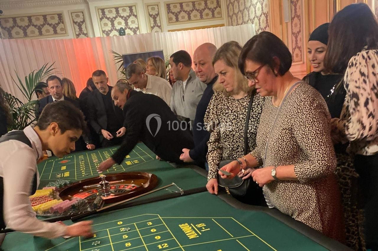 Des personnes jouent à la roulette dans un casino, entourées d'une ambiance élégante et lumineuse.