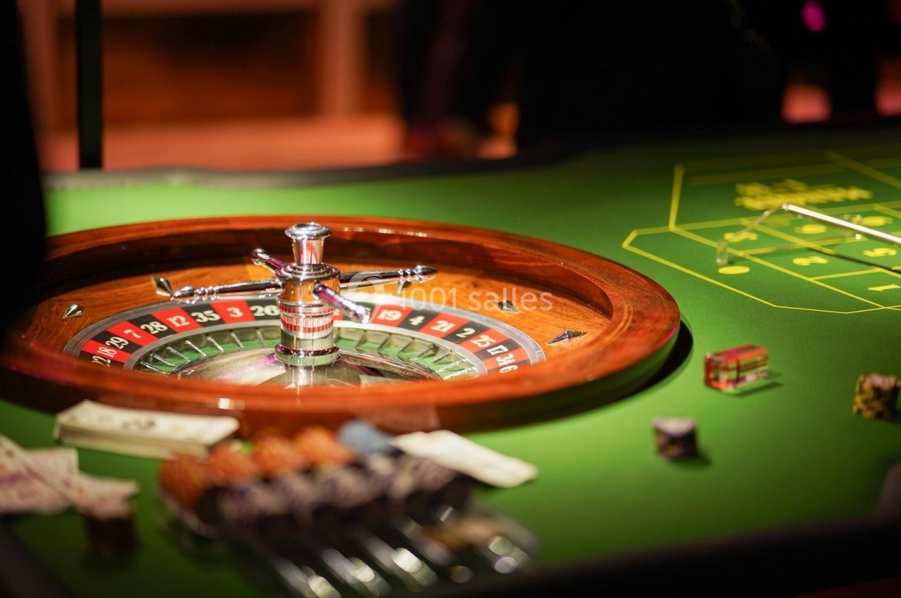 Roulette en bois sur une table de casino avec jetons et cartes visibles en arrière-plan.