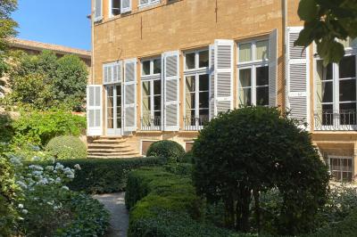 Hall d'entrée avec murs clairs, meubles en bois ancien et escalier montant à droite.
