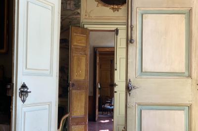 Hall d'entrée avec murs clairs, meubles en bois ancien et escalier montant à droite.