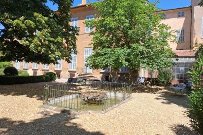 Hall d'entrée avec murs clairs, meubles en bois ancien et escalier montant à droite.
