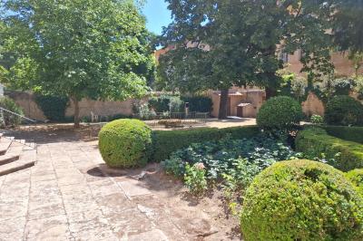 Hall d'entrée avec murs clairs, meubles en bois ancien et escalier montant à droite.