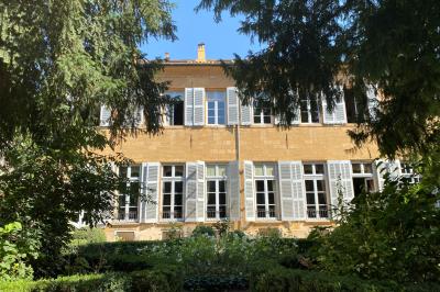 Hall d'entrée avec murs clairs, meubles en bois ancien et escalier montant à droite.