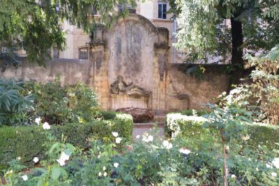 Hall d'entrée avec murs clairs, meubles en bois ancien et escalier montant à droite.