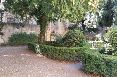 Hall d'entrée avec murs clairs, meubles en bois ancien et escalier montant à droite.