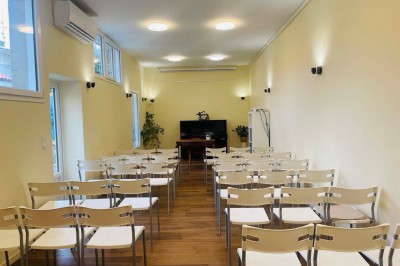 Salle lumineuse avec des tapis de yoga violets alignés sur un sol en bois, un piano et des décorations en arrière-plan.