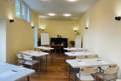 Salle lumineuse avec des tapis de yoga violets alignés sur un sol en bois, un piano et des décorations en arrière-plan.