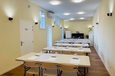 Salle lumineuse avec des tapis de yoga violets alignés sur un sol en bois, un piano et des décorations en arrière-plan.