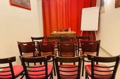 Salle lumineuse avec des tapis de yoga violets alignés sur un sol en bois, un piano et des décorations en arrière-plan.