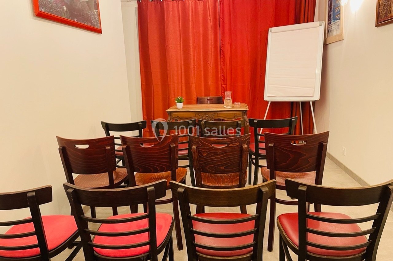 Salle avec des chaises en bois disposées face à un tableau blanc, devant un rideau rouge.