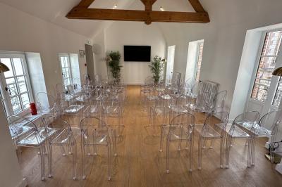 Salle de réunion lumineuse avec table en bois, quatre chaises, un tableau de présentation et une fenêtre donnant sur des…
