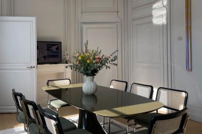 Salle de réunion lumineuse avec table en bois, quatre chaises, un tableau de présentation et une fenêtre donnant sur des…