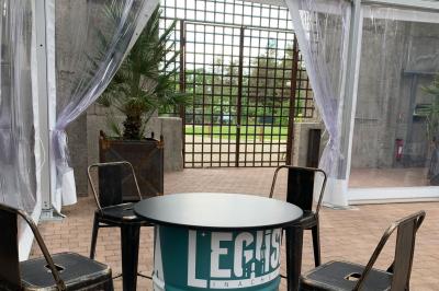 Salle équipée de plans de travail en inox, évier et carrelage gris, avec un panneau ’L'Eglise’ au mur.