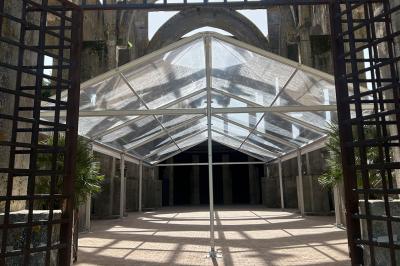 Salle équipée de plans de travail en inox, évier et carrelage gris, avec un panneau ’L'Eglise’ au mur.