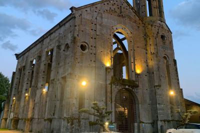 Salle équipée de plans de travail en inox, évier et carrelage gris, avec un panneau ’L'Eglise’ au mur.