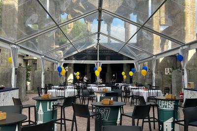 Salle équipée de plans de travail en inox, évier et carrelage gris, avec un panneau ’L'Eglise’ au mur.