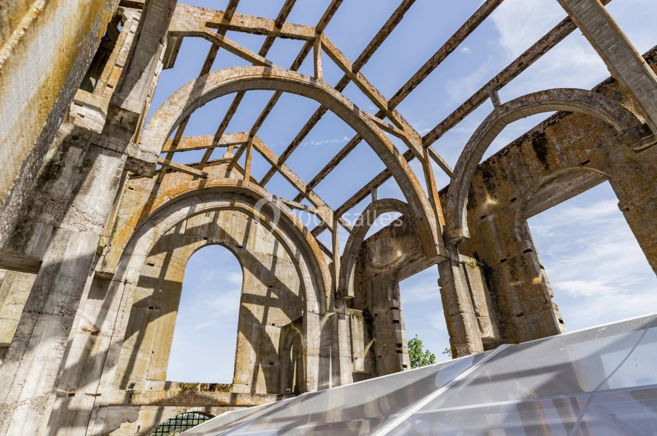 Vestiges d'une structure en pierre avec des arcs et des colonnes, partiellement couverts par une bâche transparente.