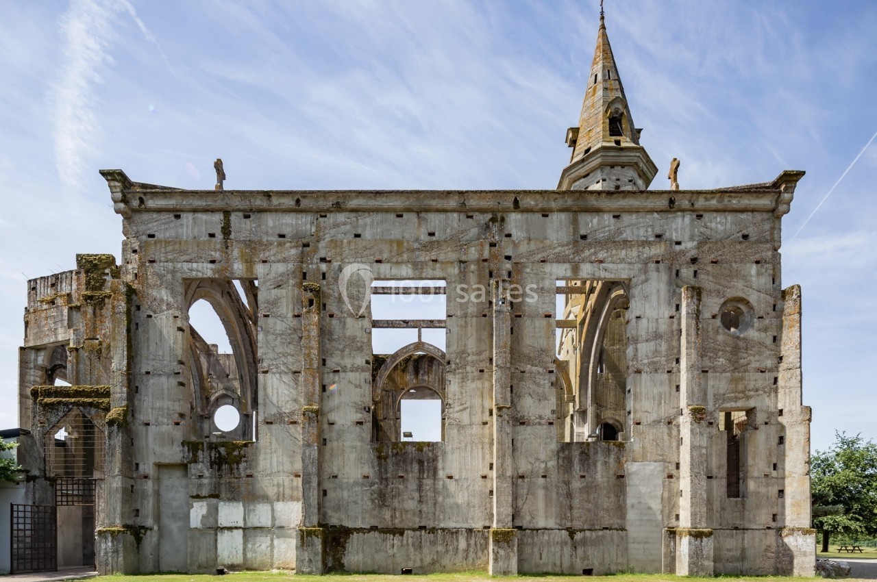 Ruines d'une église en pierre avec des arches et un clocher, sous un ciel bleu dégagé.